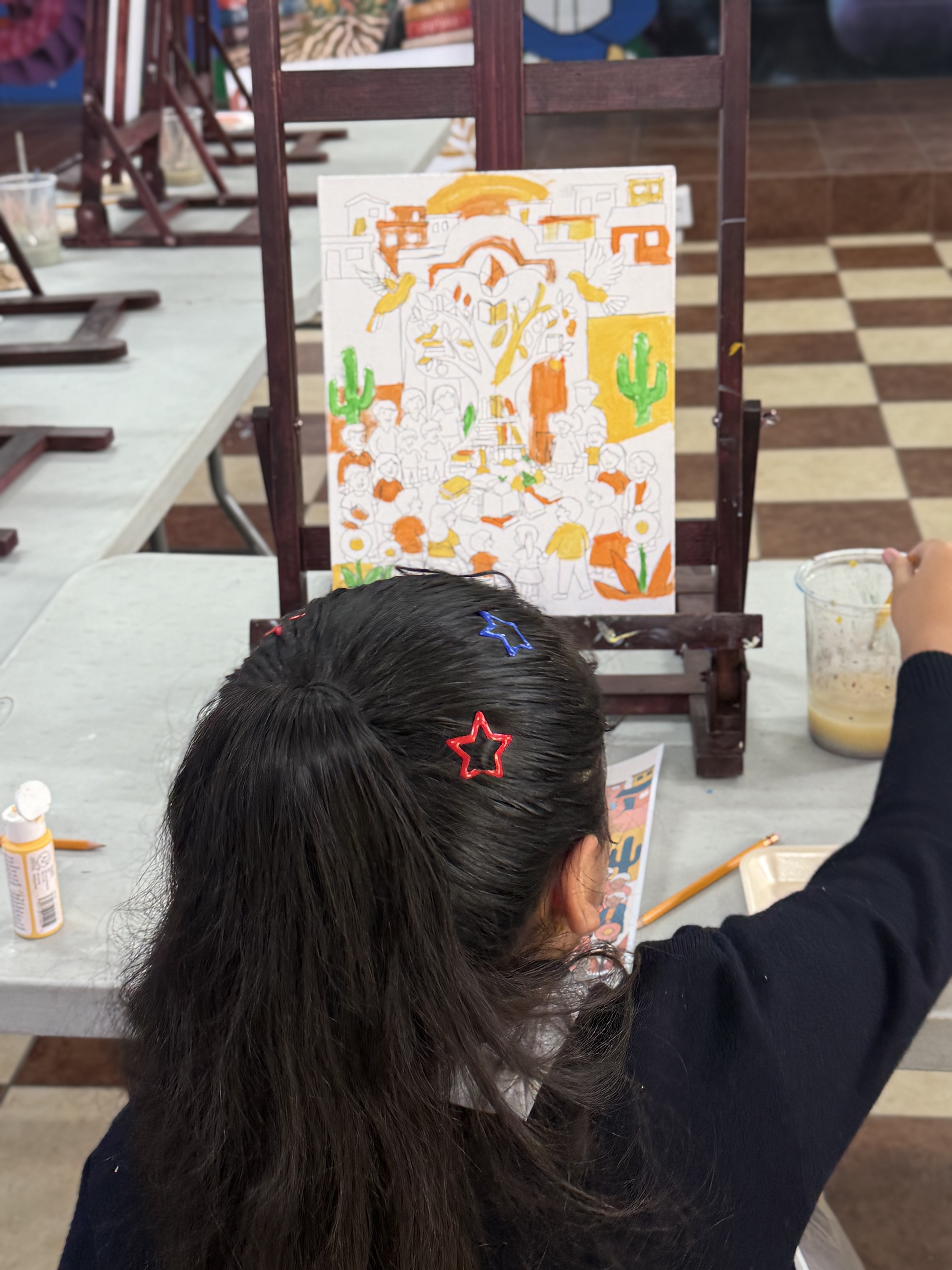 Niñas y niños de la Primaria Gregorio Torres Quintero pintando en caballetes durante una clase de arte de Bibliotecas Raíz